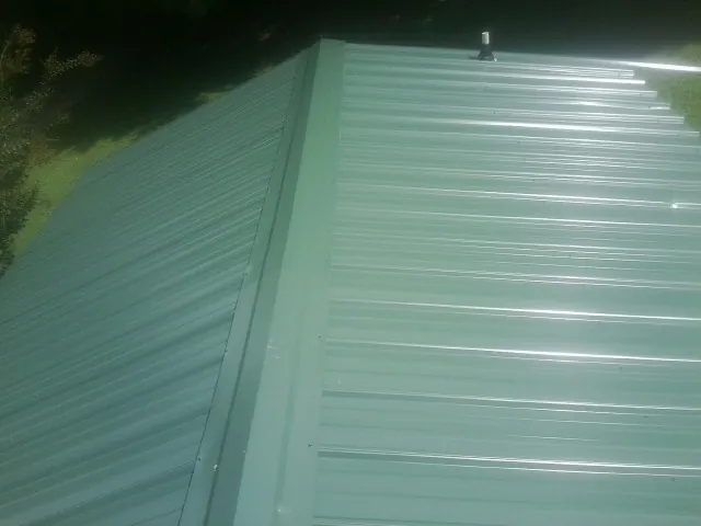 New green metal panels meeting at the ridge of a roof — Flat Roof Repair work by our crew in Oak Park