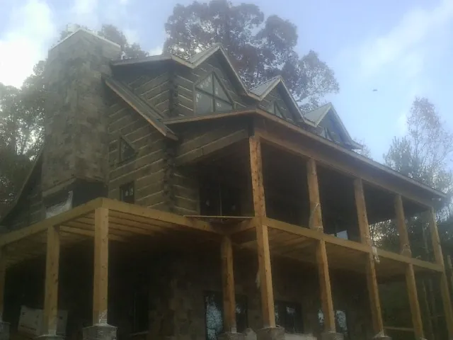 Stone chimney and dormers on a large log home with a timber porch in Oak Park